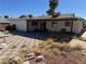 Backyard featuring a covered patio, brick and red gravel areas, and minimal landscaping under a clear blue sky at 4442 Bennett Dr, Las Vegas, NV 89121