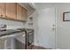 Laundry room with modern stainless steel washer and dryer units, cabinetry, door at 5465 Cardinal Ridge Ct # 103, Las Vegas, NV 89149