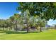 Community playground with colorful play structures and covered picnic area surrounded by lush green space and mature trees at 6232 Lautman Ridge Ct, Las Vegas, NV 89141