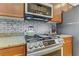 Stove top in a kitchen with stainless steel appliances, granite counters, and subway tile backsplash at 7609 Trimming Ct, Las Vegas, NV 89149