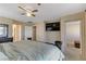 This bright main bedroom has a ceiling fan, mounted TV, and views of an entry and bathroom at 7609 Trimming Ct, Las Vegas, NV 89149