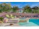 Backyard hot tub, tanning chairs, lush landscaping, rock features, and brick perimeter fence at 8093 Luna Sera Ave, Las Vegas, NV 89178