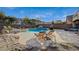 Backyard pool with tanning ledge, waterfall feature, hot tub, tanning chairs, and patio seating area at 8093 Luna Sera Ave, Las Vegas, NV 89178