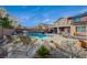 Backyard pool area with tanning chairs, tanning ledge, lush landscaping, waterfall feature, and barbecue grill at 8093 Luna Sera Ave, Las Vegas, NV 89178