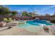 Backyard pool featuring rock features, tanning ledge, hot tub, lush landscaping, and brick perimeter fence at 8093 Luna Sera Ave, Las Vegas, NV 89178
