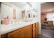 Charming bathroom featuring dual sinks, wood cabinets and peek into a perfectly decorated bedroom at 8890 Bonneville Peak Ct, Las Vegas, NV 89148