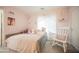 Bright bedroom with a cozy daybed, rocking chair, and soft pink walls, creating a comfortable space at 8890 Bonneville Peak Ct, Las Vegas, NV 89148