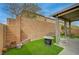 Well-maintained backyard featuring a covered patio, a brick wall, artificial turf, and space for outdoor seating at 9180 Wine Cellar Ave, Las Vegas, NV 89148