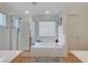 Bright bathroom features a soaking tub, separate glass enclosed shower, and neutral tile at 9180 Wine Cellar Ave, Las Vegas, NV 89148