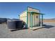 Tan outbuilding with a green trim and a wooden porch, water tank, and gravel at 3341 S Big Sky Way, Pahrump, NV 89048