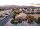 Aerial view showcasing the neighborhood homes with terracotta roofs and solar panels, complemented by verdant landscaping and mountain views at 4401 Lilac Glen Dr, Las Vegas, NV 89129