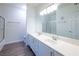 Bright bathroom with dual sink vanity, large mirror, tub/shower and gray wood-look floors at 6160 Rumrill St # 201, Las Vegas, NV 89113