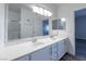 Bathroom with dual sinks, large mirror and vanity with white cabinets and gray wood-look floors at 6160 Rumrill St # 201, Las Vegas, NV 89113