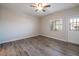 Cozy bedroom featuring gray wood flooring, a ceiling fan, a window for natural light, and a white door at 6160 Rumrill St # 201, Las Vegas, NV 89113