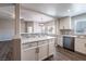 Open concept kitchen with white cabinets, gray backsplash, gray wood flooring, and eat in bar area at 6160 Rumrill St # 201, Las Vegas, NV 89113