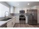 Bright kitchen with white cabinets, stainless steel appliances, gray backsplash, and gray wood flooring at 6160 Rumrill St # 201, Las Vegas, NV 89113