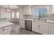 Modern kitchen featuring white cabinets, stainless steel appliances, gray backsplash, and luxury gray wood flooring at 6160 Rumrill St # 201, Las Vegas, NV 89113