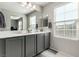 Bathroom featuring double sinks, gray cabinets, tiled floors, and views to the outdoors at 703 Sleeping City Ave, Henderson, NV 89015