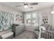 Cozy Bedroom with neutral tones, ceiling fan, crib, and changing table with ample natural light at 703 Sleeping City Ave, Henderson, NV 89015