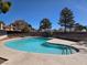 Inviting community pool featuring clear blue water, ample deck space, and mature trees in a fenced enclosure at 741 Bourbon St # E3, Pahrump, NV 89048