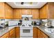 Traditional kitchen boasts wood cabinets, granite countertops, and white appliances at 1455 E Katie Ave # A21, Las Vegas, NV 89119