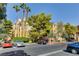 Exterior view of a home with multiple parked cars and large mature shade trees at 210 E Flamingo Rd # 326, Las Vegas, NV 89169