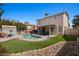 Well-maintained backyard featuring a pool, patio with cover, artificial grass, and rock landscaping at 2199 Maple Shade St, Henderson, NV 89002