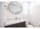 Stylish half bath with modern vanity, round mirror, and textured tile walls at 2514 Spergola St, Henderson, NV 89044