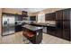 An open-concept kitchen with dark wood cabinets, stainless steel appliances, and tile flooring at 33 Via Di Mello, Henderson, NV 89011