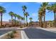 A long, paved street lined with palm trees leads to a gated entry under a clear sky at 33 Via Di Mello, Henderson, NV 89011
