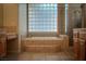Luxurious bathroom featuring a soaking tub, glass block window for privacy, and tile surround at 504 Pinnacle Heights Ln, Las Vegas, NV 89144