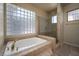 Bathroom with a large tub, glass-enclosed shower, and decorative tiled walls around the window at 504 Pinnacle Heights Ln, Las Vegas, NV 89144