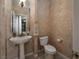 Elegant half bathroom features textured walls, a pedestal sink, and a toilet with modern fixtures at 504 Pinnacle Heights Ln, Las Vegas, NV 89144