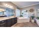 Bright bathroom featuring a double vanity, soaking tub with decorative accents, and wood-look tile flooring at 6206 Rio Camuy Ave, Las Vegas, NV 89131