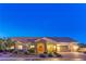 Charming single-story home with a stone-accented entryway and well-lit three-car garage at twilight at 6206 Rio Camuy Ave, Las Vegas, NV 89131