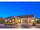 Warm single-story home at dusk featuring a stone-detailed entryway, three-car garage, and manicured front yard at 6206 Rio Camuy Ave, Las Vegas, NV 89131