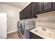 Well-lit laundry room featuring a washer, dryer, utility sink, and ample cabinet space at 6206 Rio Camuy Ave, Las Vegas, NV 89131