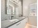 Bathroom with double sinks, subway tile backsplash, and a large framed mirror at 9314 Indian Corn Ct # 102, Las Vegas, NV 89178