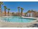 A pristine community pool is surrounded by lounge chairs and tall swaying palm trees at 9314 Indian Corn Ct # 102, Las Vegas, NV 89178