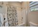 Cozy bathroom featuring a tub-shower combo with patterned curtain and a window providing natural light at 9940 Heather Moore Ave, Las Vegas, NV 89166