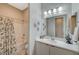 Bright bathroom featuring a white vanity with white countertops, decorative mirror and a tub-shower combo with patterned curtain at 9940 Heather Moore Ave, Las Vegas, NV 89166