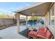 Covered patio includes outdoor seating with a view of the sparkling pool and landscaped yard at 10638 La Spezia Way, Las Vegas, NV 89141