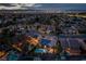 Twilight aerial shot showcases a well-lit neighborhood with lush trees, pools, and city lights creating a peaceful ambiance at 2287 Moresca Ave, Henderson, NV 89052