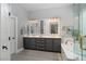 Elegant bathroom featuring double sinks with grey cabinetry, decorative mirrors, and a soaking tub at 2287 Moresca Ave, Henderson, NV 89052