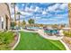 Lush backyard with a pool, spa, comfortable seating, and vibrant landscaping at 2824 Soaring Peak Ave, Henderson, NV 89052