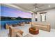 Expansive covered patio with ceiling fan and seating area overlooking lake at sunset at 32 Grand Corniche Dr, Henderson, NV 89011
