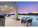 Covered patio with an outdoor kitchen and dining area overlooking a serene lake at 32 Grand Corniche Dr, Henderson, NV 89011