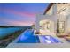 An outside view of an illuminated pool area with lake view and an incredible sunset in the background at 32 Grand Corniche Dr, Henderson, NV 89011