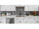 Modern kitchen featuring white cabinets, gray backsplash, stainless steel dishwasher, and marble countertops at 3492 Edison Ave, Las Vegas, NV 89121
