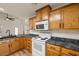 Kitchen featuring wood cabinets, dark countertops, and white appliances with wood flooring throughout at 5050 Nw Valdez Ct, Pahrump, NV 89060